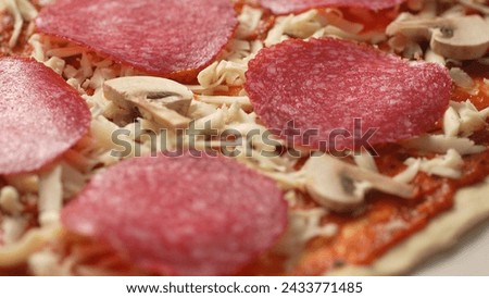 Raw Mushrooms with Salami and Cheese on Pizza Dough. Close-up, shallow dof.