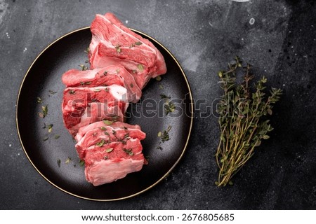 Raw mutton cut rib chops, fresh lamb meat with herbs for grilling. black background. top view.
