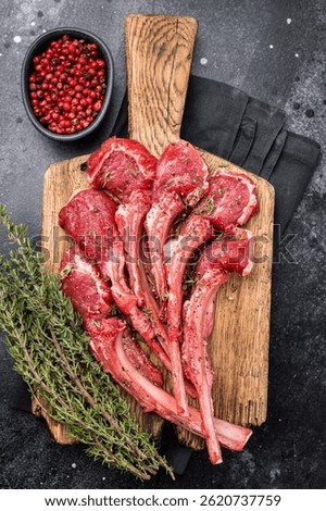 Raw mutton cutlets, fresh lamb meat chops on a wooden board. black background. top view.