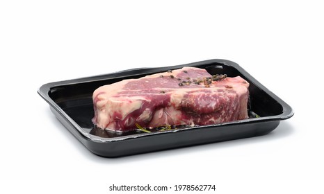 Raw New York beef steak is packed in a plastic container and vacuum sealed. Long-term storage striploin meat. White background - Powered by Shutterstock