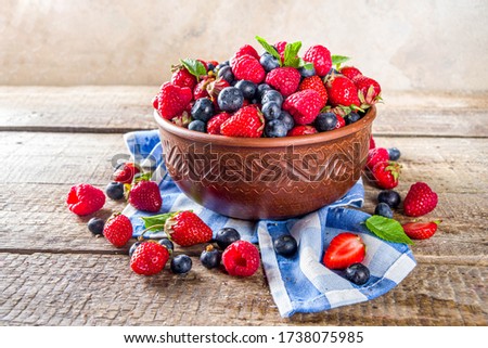 Raw Organic Assorted Various Fresh Berries with Blueberries Raspberries and Strawberries on rustic wooden background