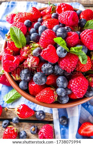 Raw Organic Assorted Various Fresh Berries with Blueberries Raspberries and Strawberries on rustic wooden background