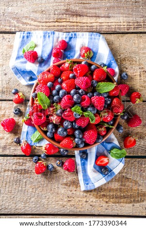 Raw Organic Assorted Various Fresh Berries with Blueberries Raspberries and Strawberries on rustic wooden background