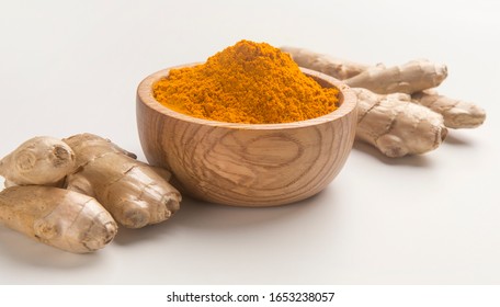 Raw organic essential spice Turmeric or Curcuma in wooden bowl with root on white background, panorama