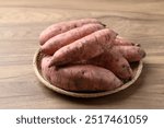 Raw organic Japanese sweet potatoes in basket on wooden background