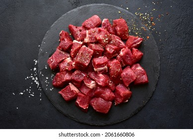 Raw organic meat ( beef or lamb ) on a black slate board. Top view with copy space. - Shutterstock ID 2061660806