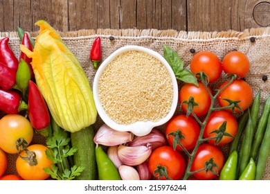 Raw Organic Millet In Bowl And Vegetables On The Wooden Table