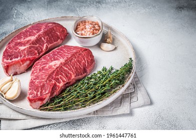 Raw Oyster Top Blade Or Flat Iron Roast Beef Meat Steaks On A Plate With Herbs. White Background. Top View. Copy Space