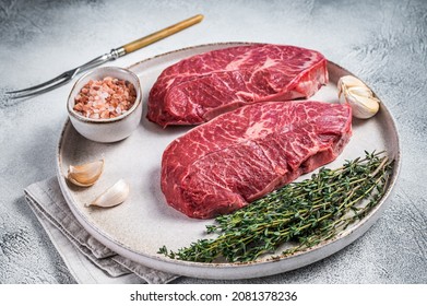 Raw Oyster Top Blade Or Flat Iron Roast Beef Meat Steaks On A Plate With Herbs. White Background. Top View