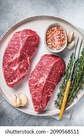 Raw Oyster Top Blade Or Flat Iron Roast Beef Meat Steaks On A Plate With Herbs. White Background. Top View