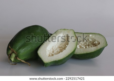 Raw papaya or unripe green papaya. Popular for cooking salads and side dishes. Shot with half cut pieces on white background