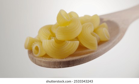 Raw Pasta Shells on Wooden Spoon Against Light Background - Powered by Shutterstock