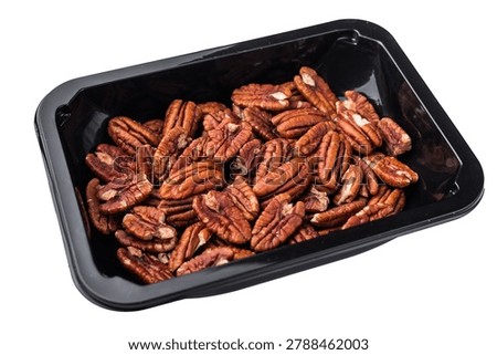 Raw pecan halves packed in a black plastic container on a clean white background creating a simple ingredient image ideal for culinary stock themes.