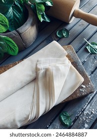 Raw phyllo dough on a rustic wooden table. Thin filo dough for baking, for pie and cakes.