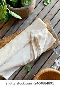 Raw phyllo dough on a rustic wooden table. Thin filo dough for baking, for pie and cakes.