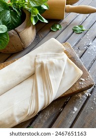 Raw phyllo dough on a rustic wooden table. Thin filo dough for baking, for pie and cakes.