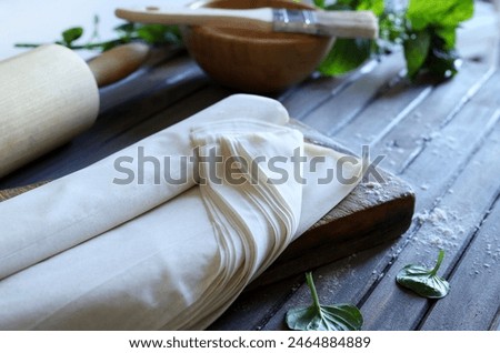Raw phyllo dough on a rustic wooden table. Thin filo dough for baking, for pie and cakes.