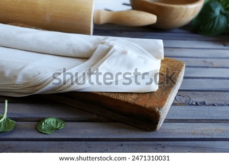 Raw phyllo dough on a rustic wooden table. Thin filo dough for baking, for pie and cakes.