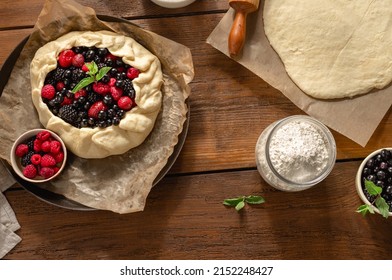 Raw pie cake with fruit strawberry, blueberry, blackberry and raspberry on a wooden table top view. Ingredients for cooking homemade fruit tart