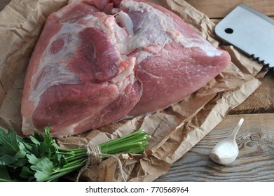 raw piece of pork big ham and a big chopping knife on a wooden rustic background - Powered by Shutterstock