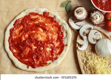 Raw Pizza Dough With Tomato Sauce, Ingredients (cheese And Mushrooms) And Spices On Bright Background. Top View