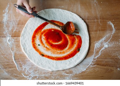 Raw Pizza And Hand Pouring Tomato Sauce