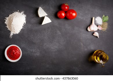 Raw pizza ingredients on the chalkboard with copy space on the center. You can put your image or inscription at the center