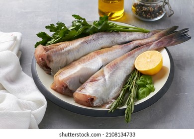 Raw Pollock Fish On Plate Lemon Parsley Rosemary Grey Background