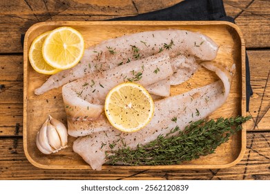 Filetes de pescado crudos de abadejo y merluza en un tablero de madera con hierbas listas para cocinar. fondo de madera.