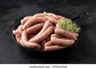Raw pork chipolata sausage in cast iron skillet frying pan