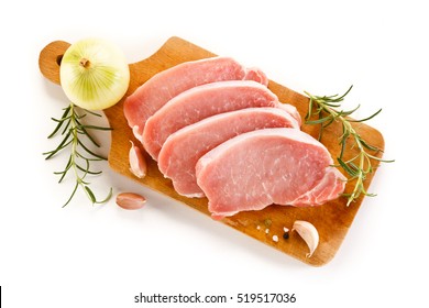 Raw pork chops on cutting board and vegetables