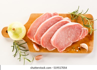 Raw Pork Chops On Cutting Board And Vegetables