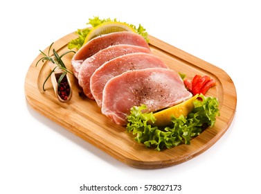 Raw pork chops on cutting board and vegetables  - Powered by Shutterstock