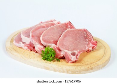 Raw Pork Loin Chops On The Wooden Plate