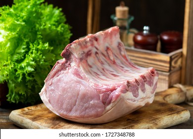 Raw pork loin meat on a wooden Board on a brown wooden table.  Rustic style. Space for text