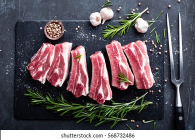raw pork meat ribs with ingredients for cooking, dark background, top view