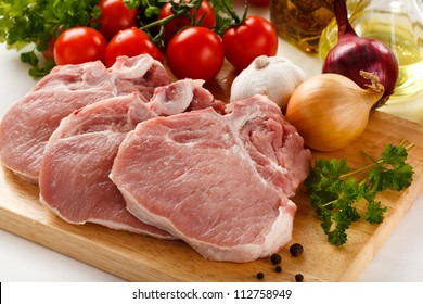 Raw pork on cutting board and vegetables - Powered by Shutterstock