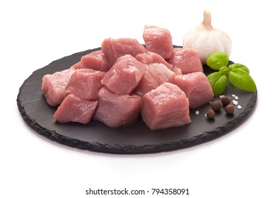 Raw pork pieces on stone plate, close-up, isolated on white background.