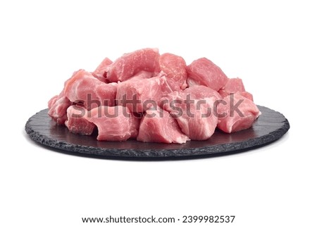 Raw pork pieces on stone plate, close-up, isolated on white background