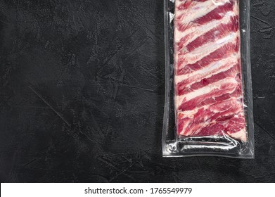 Raw pork ribs vacuum packed. Black background. Top view. Space for text