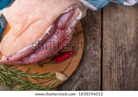 Raw pork shank with rosemary and pepper on wooden background. Space for text. View from above.