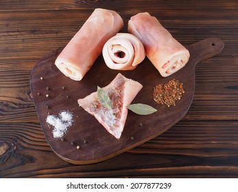 Raw pork skin with spices on a kitchen board on a dark wooden table, flat layout. Natural product for the preparation of national traditional delicacies