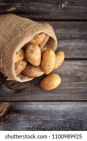 Raw Potato Food . Fresh Potatoes In An Old Sack On Wooden Background. Top View