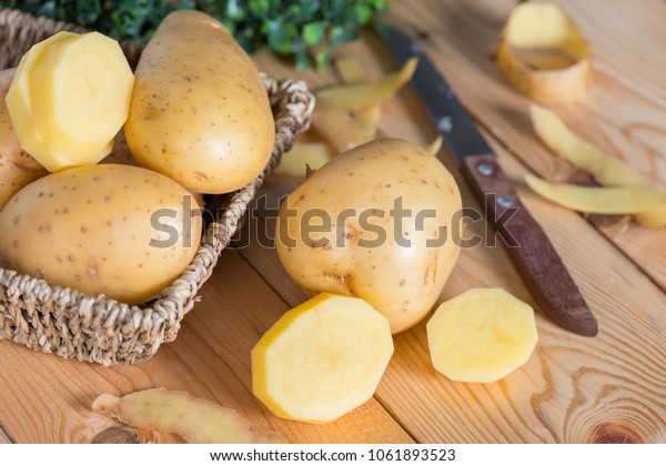 Raw potato food. Fresh potatoes on wooden\
basket, prepare for\
cooking.