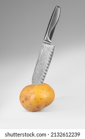 Raw potato stabbed with a pattern-welded kitchen knife in it in light back