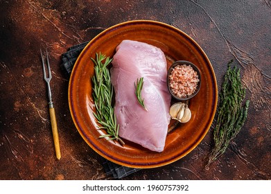 Raw Poultry Turkey Breast Fillet Meat In A Rustic Plate With Rosemary And Thyme. Dark Background. Top View