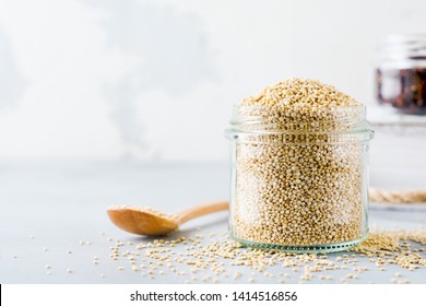 Raw quinoa grains in jar. Healthy vegetarian food on gray kitchen table. Selective focus.