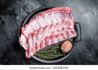 Raw rack of pork spare ribs in steel kitchen tray. Black background. Top view - Powered by Shutterstock