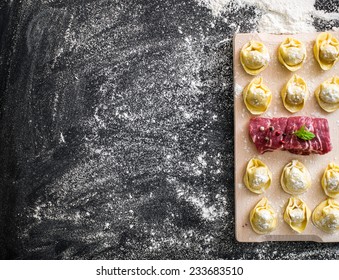 raw ravioli and different products on the black kitchen table