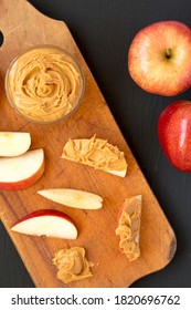 Raw Red Apples And Peanut Butter On A Rustic Wooden Board On A Black Background, Top View. Flat Lay, Overhead, From Above. 